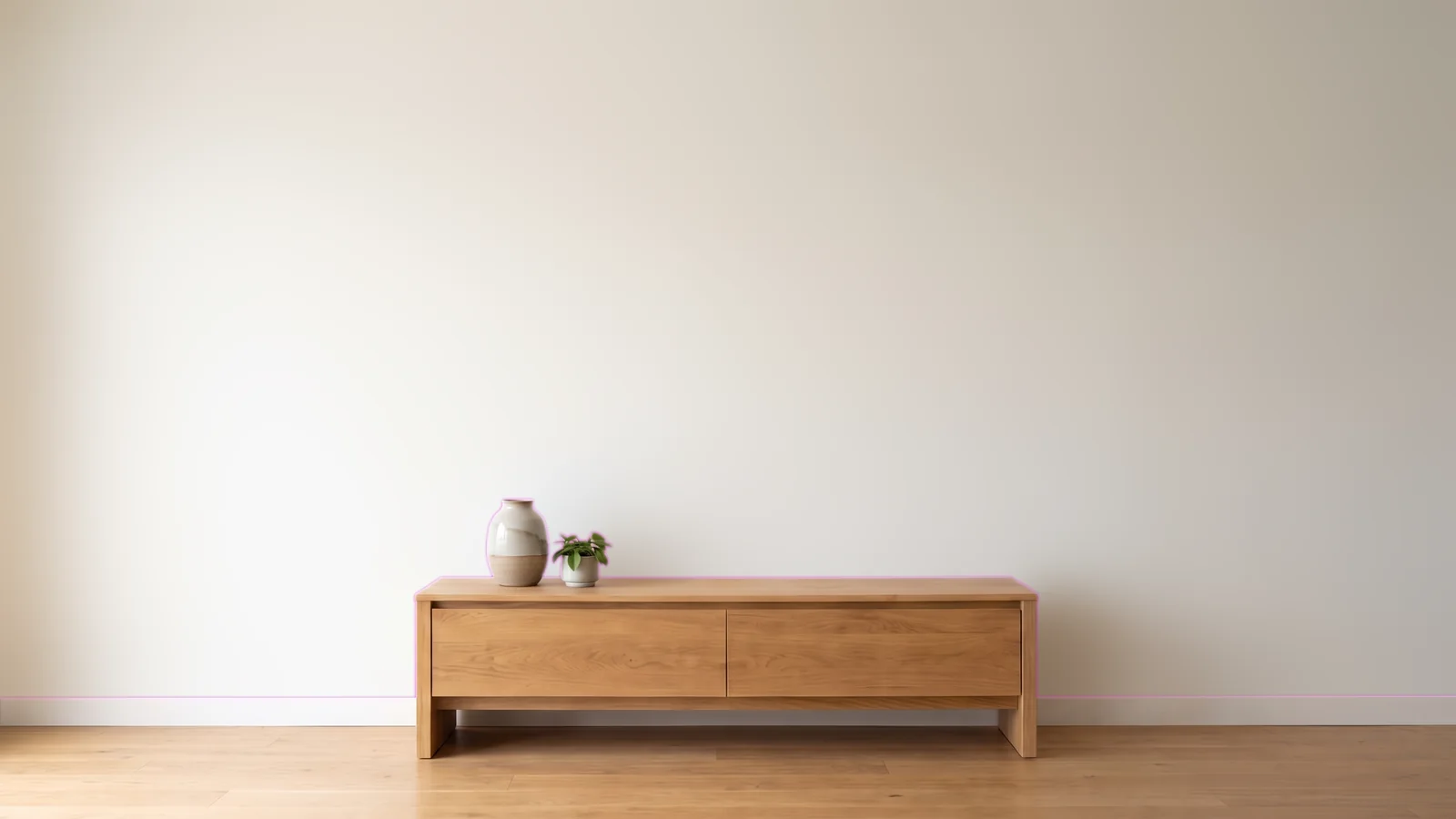 Wohnraum mit heller Wand, Sideboard und Pflanze